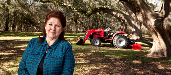 woman smiling with her mahindra tractor in the background
